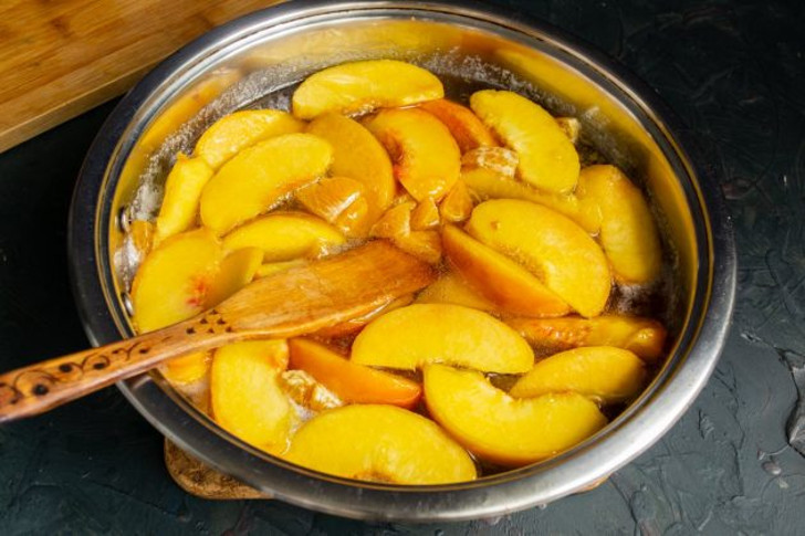 В кипящий сироп кладём нарезанные персики, на сильном огне доводим до кипения