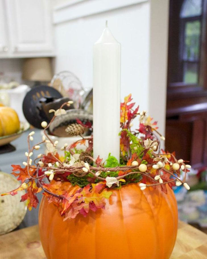 Подсвечник из тыквы, декорированный венком из листьев и веток. © THE EVERYDAY HOME